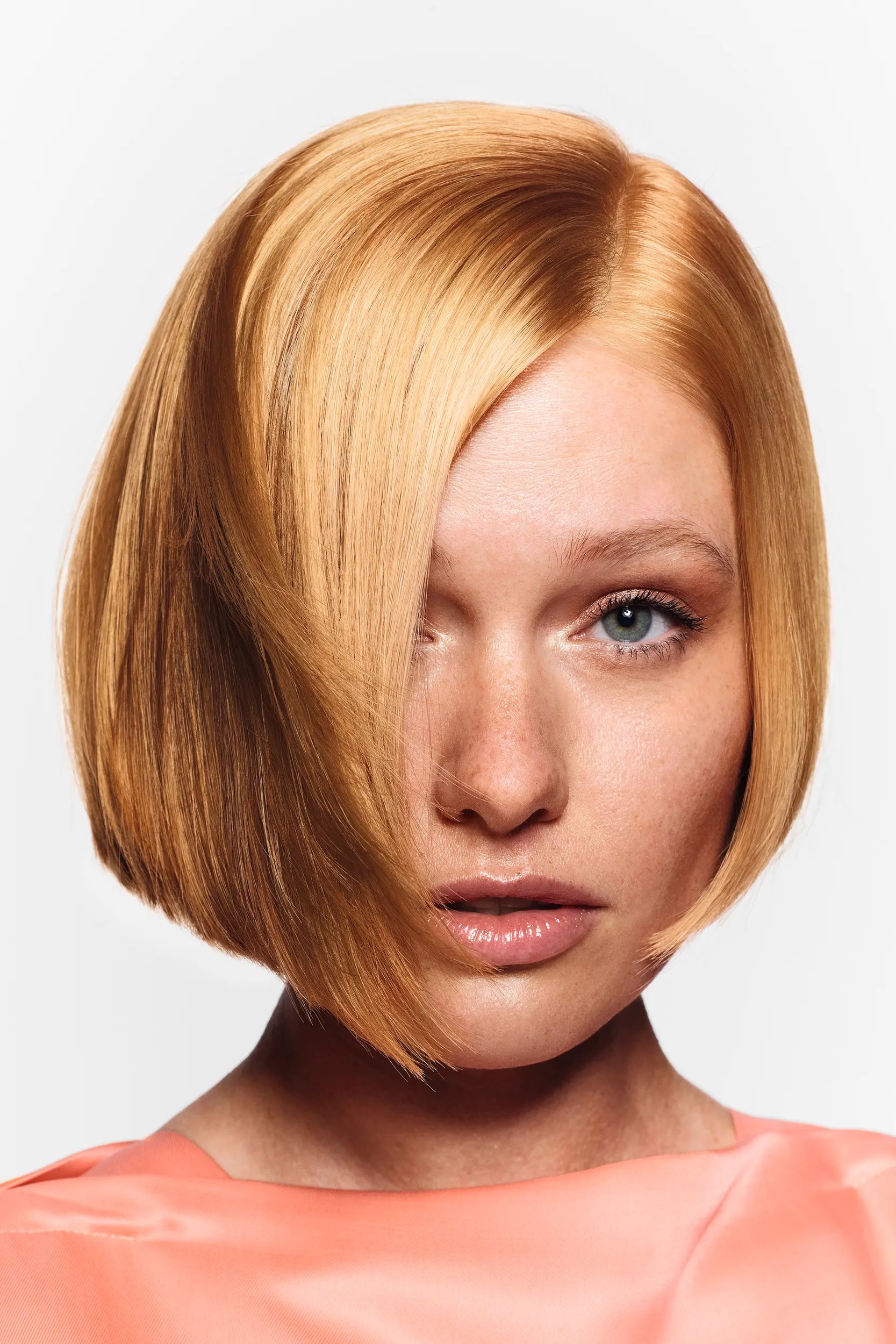 Model with sleek, high-shine golden blonde hair styled in a smooth, glass-like finish, highlighting Wella Professionals’ Golden Glass trend.
