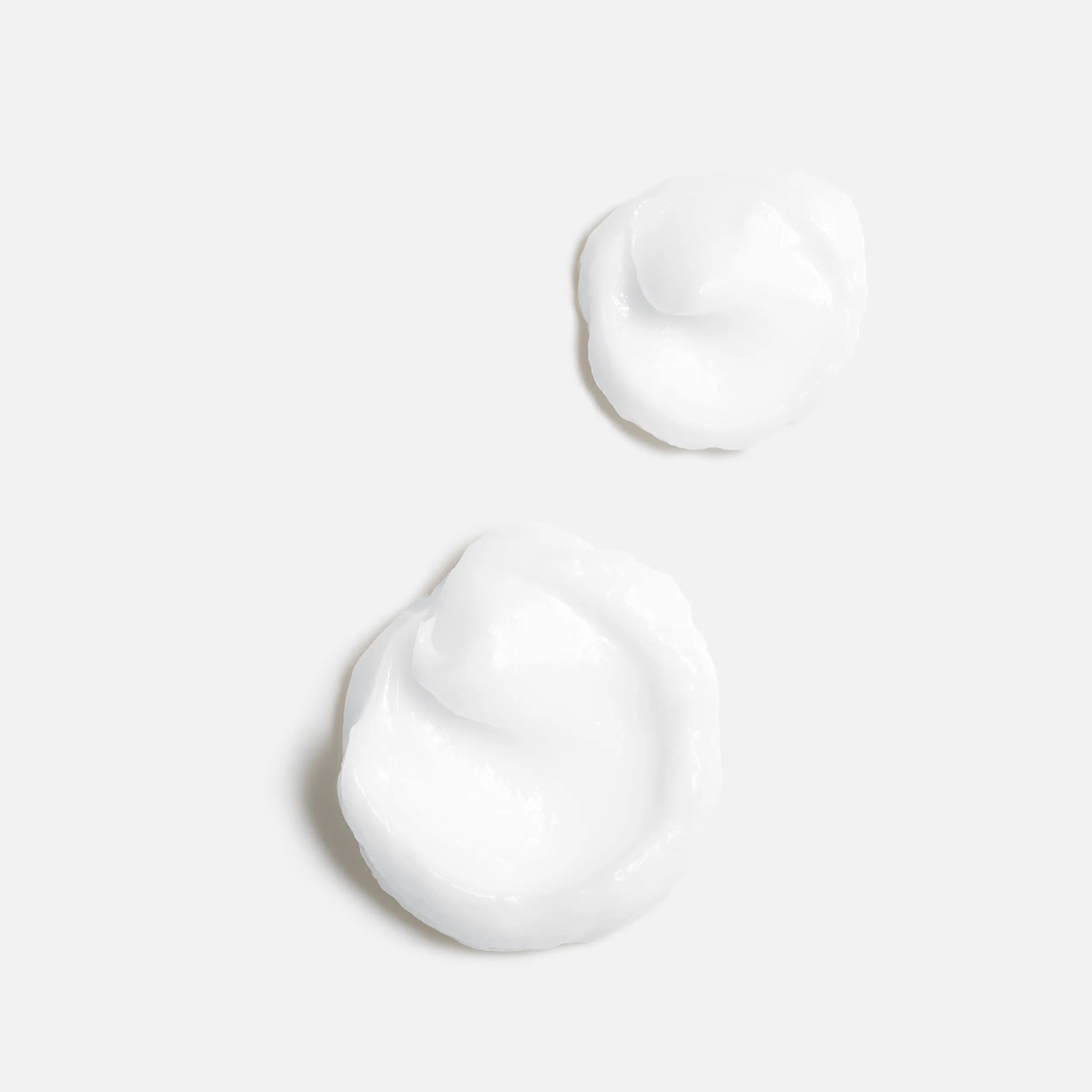 Image of two dollops of white cream, highlighting the ingredients oleic acid and panthenol and their moisturizing properties.