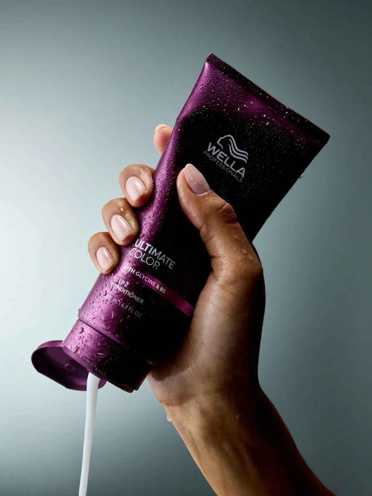 Model’s hand squeezes tube of ULTIMATE COLOR Conditioner.