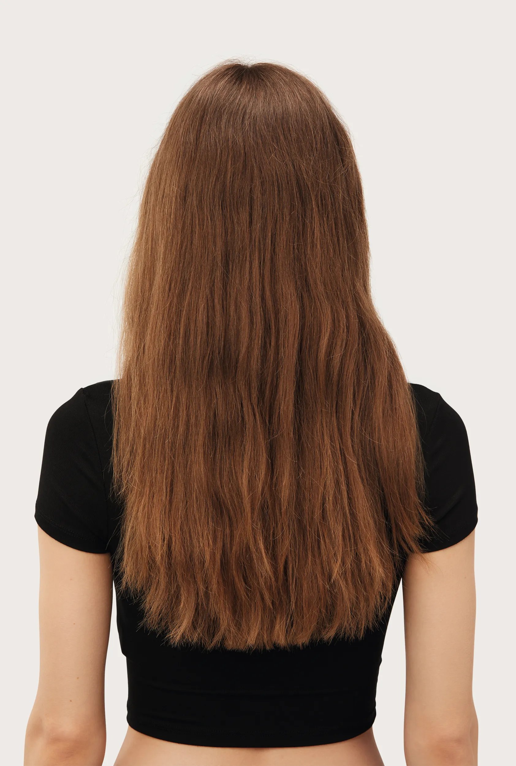 Model with long brown hair faces away from the camera