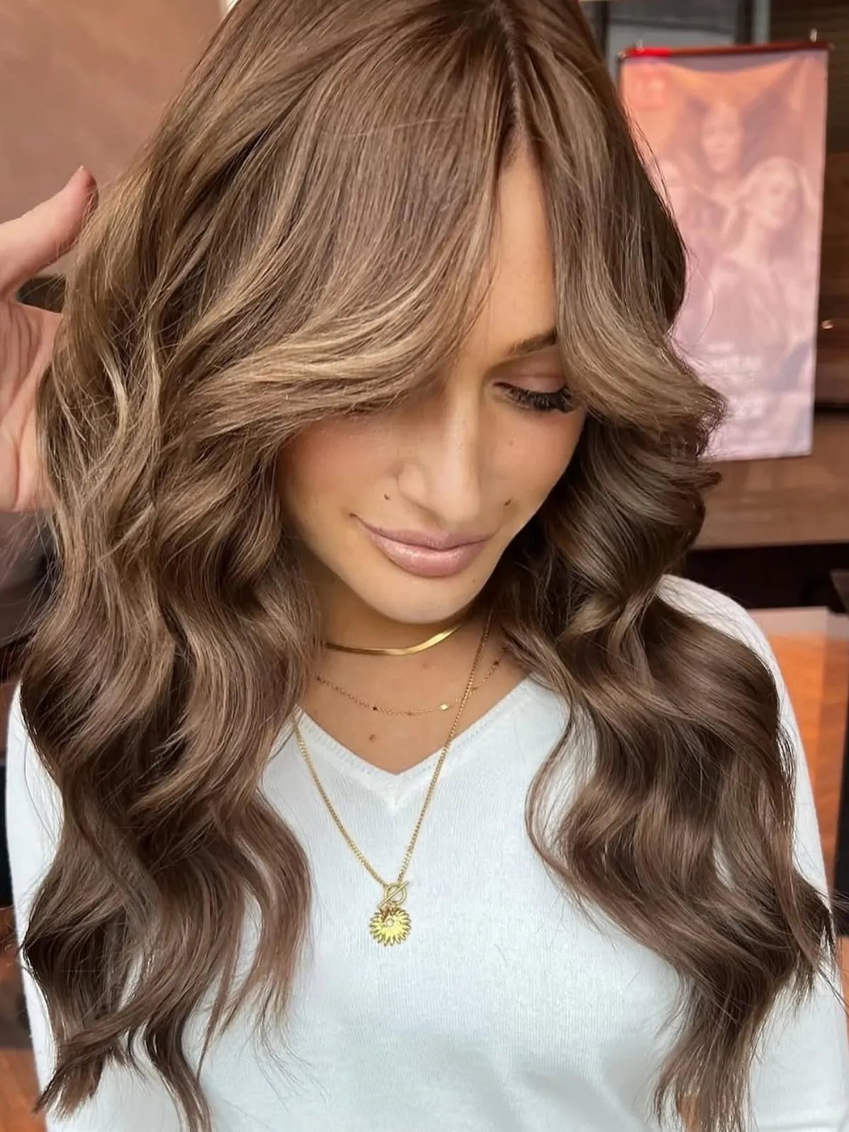 Model with a dark blonde reverse balayage, featuring golden tones through chocolate brown lengths.
