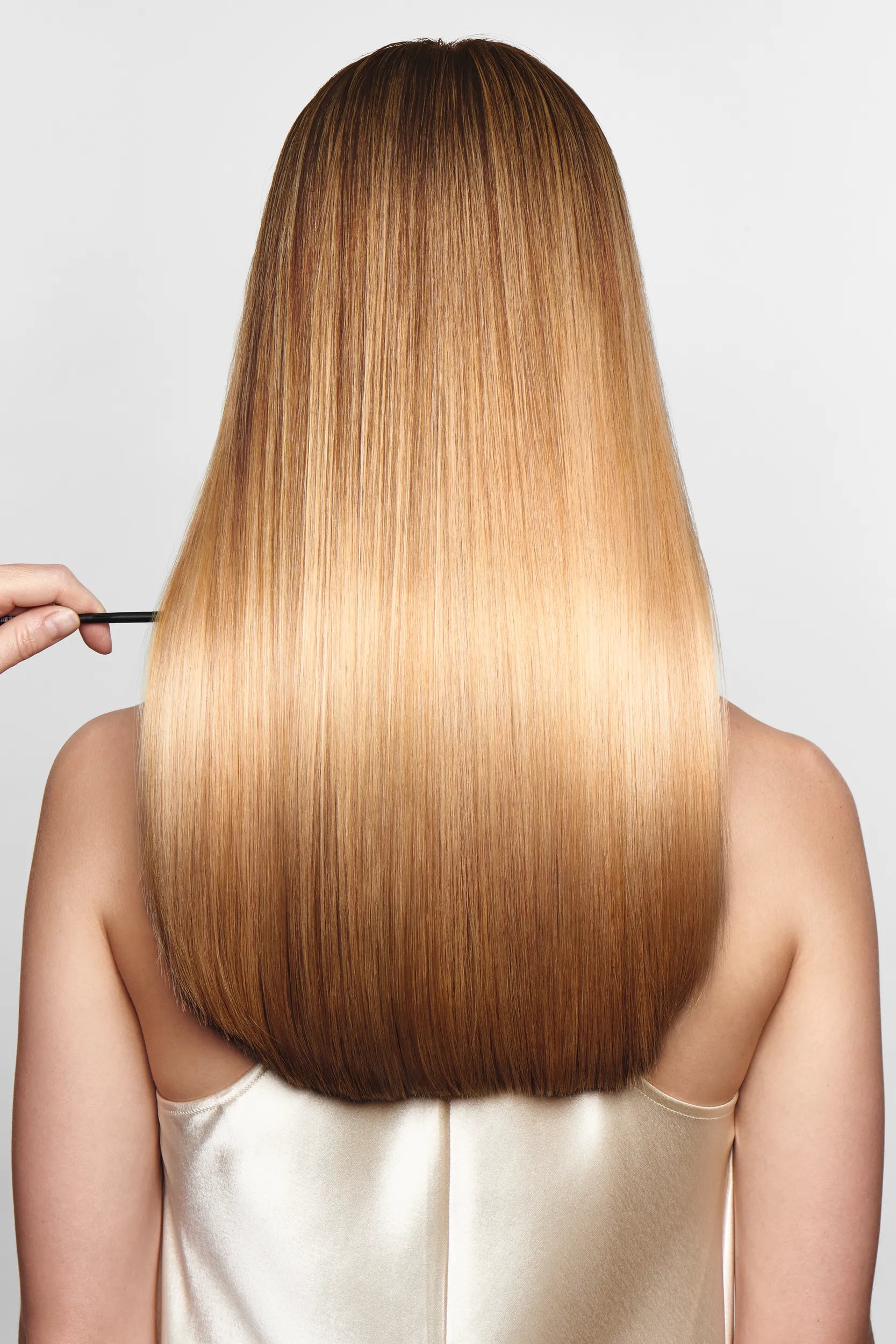 Model with back to the camera has long, golden hair that looks healthy and shiny.