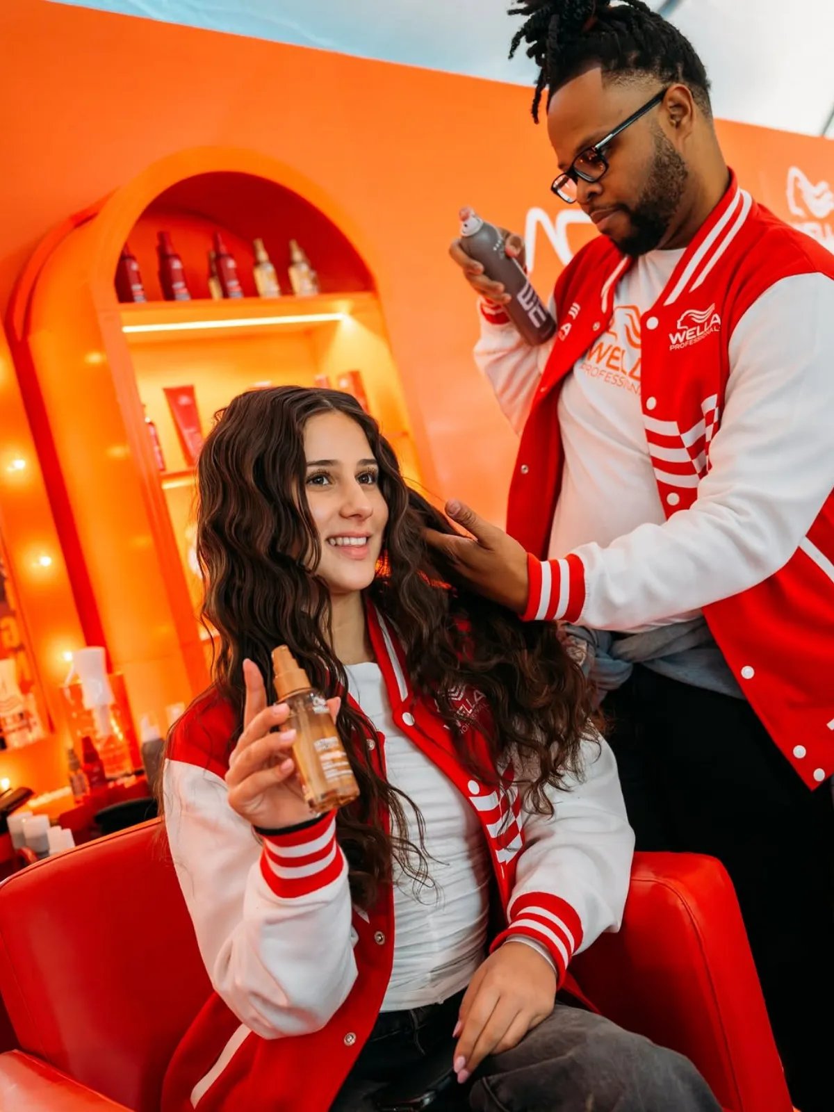 Joanne Ciconte sits in the Wella Professionals beauty pitstop, holding a bottle of ULTIMATE SMOOTH Miracle Oil Serum. 