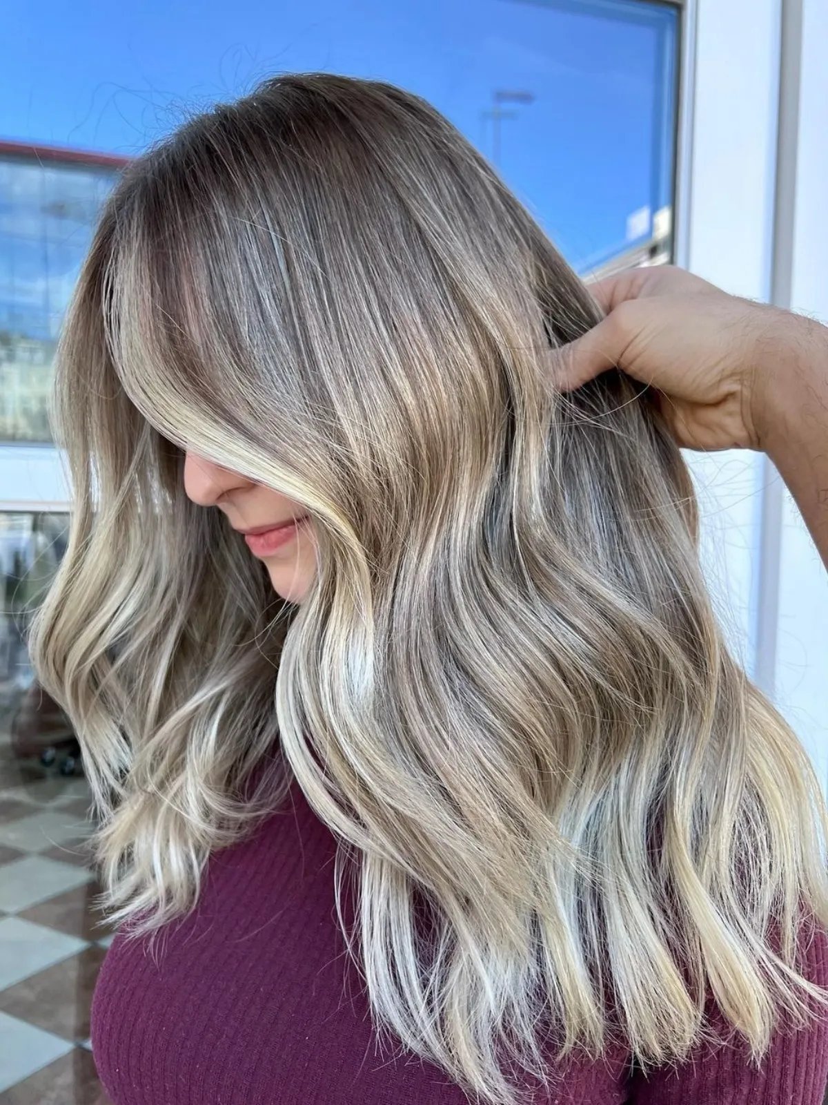 Model with long, loosely waved, neutral blonde hair featuring ashy, beige ribbons.