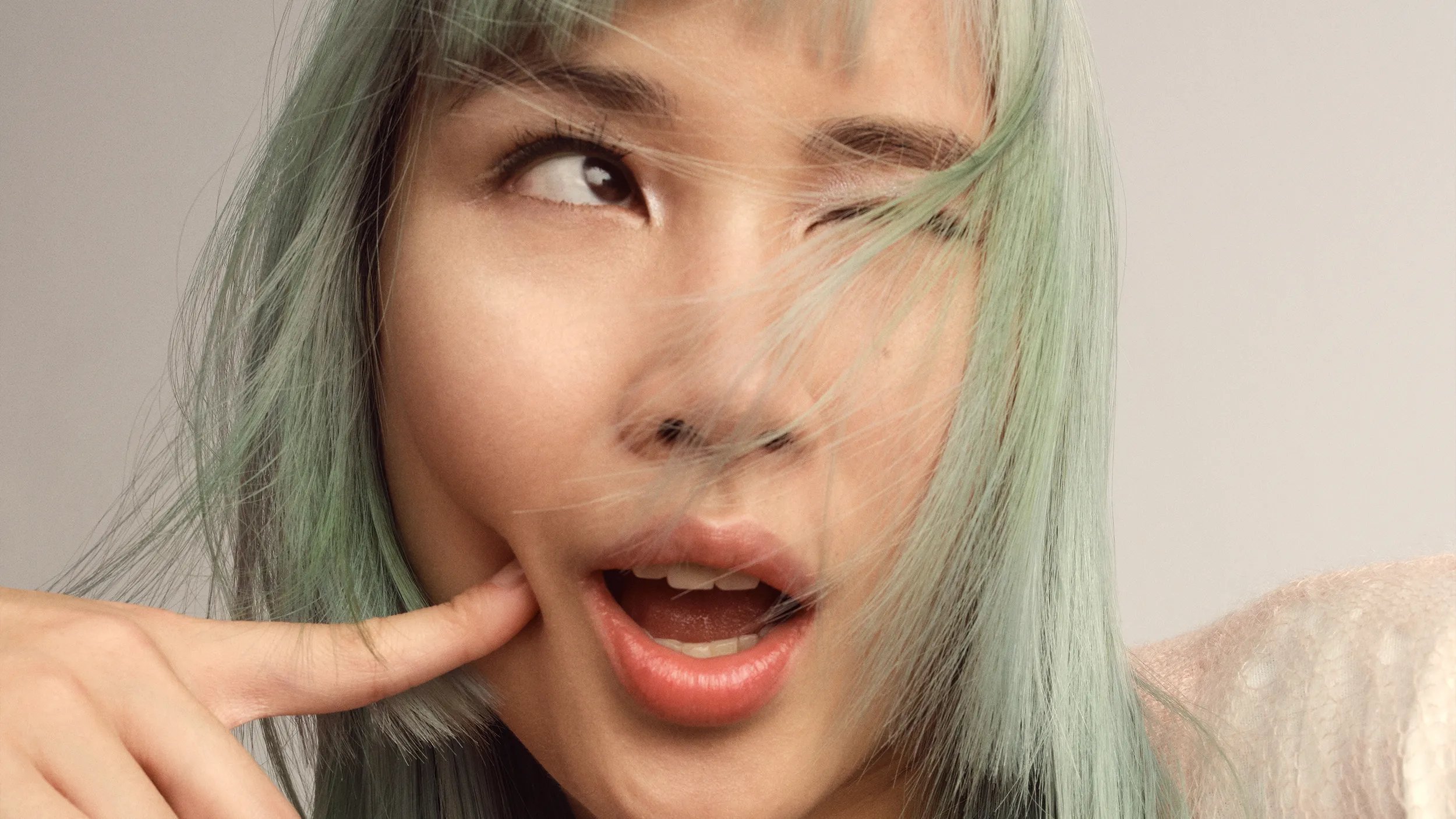 Model with long, sleek, silver-lavender hair and blunt bangs poses against a neutral background. 