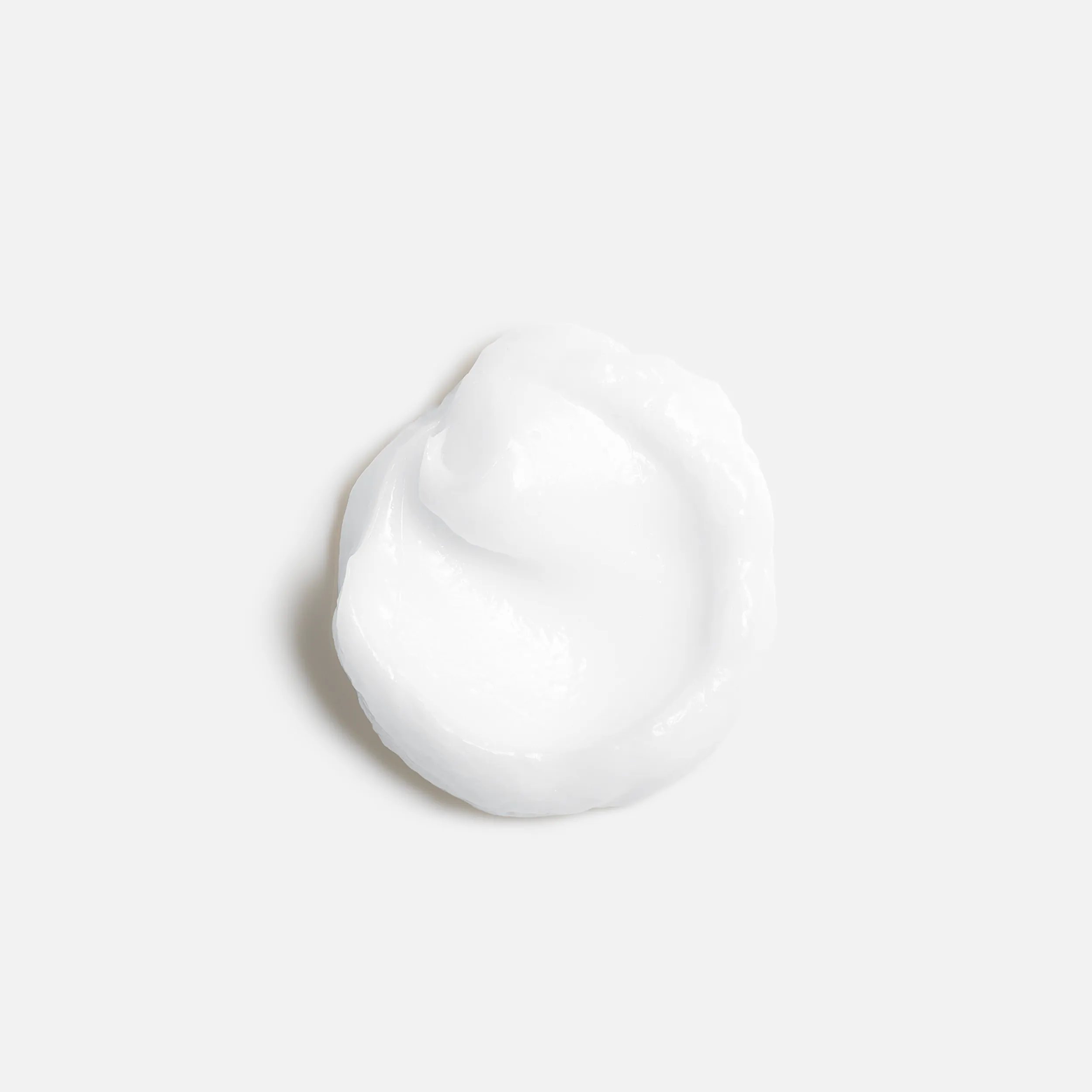 A small dollop of white cream against a plain white background.