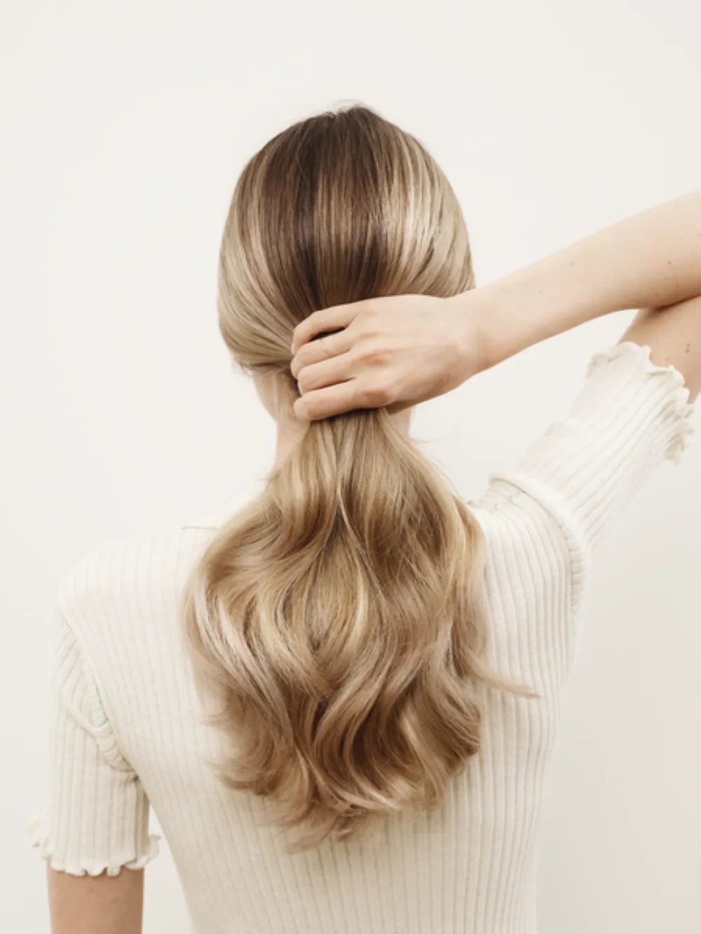 Model with long, wavy blonde hair seen from the back.