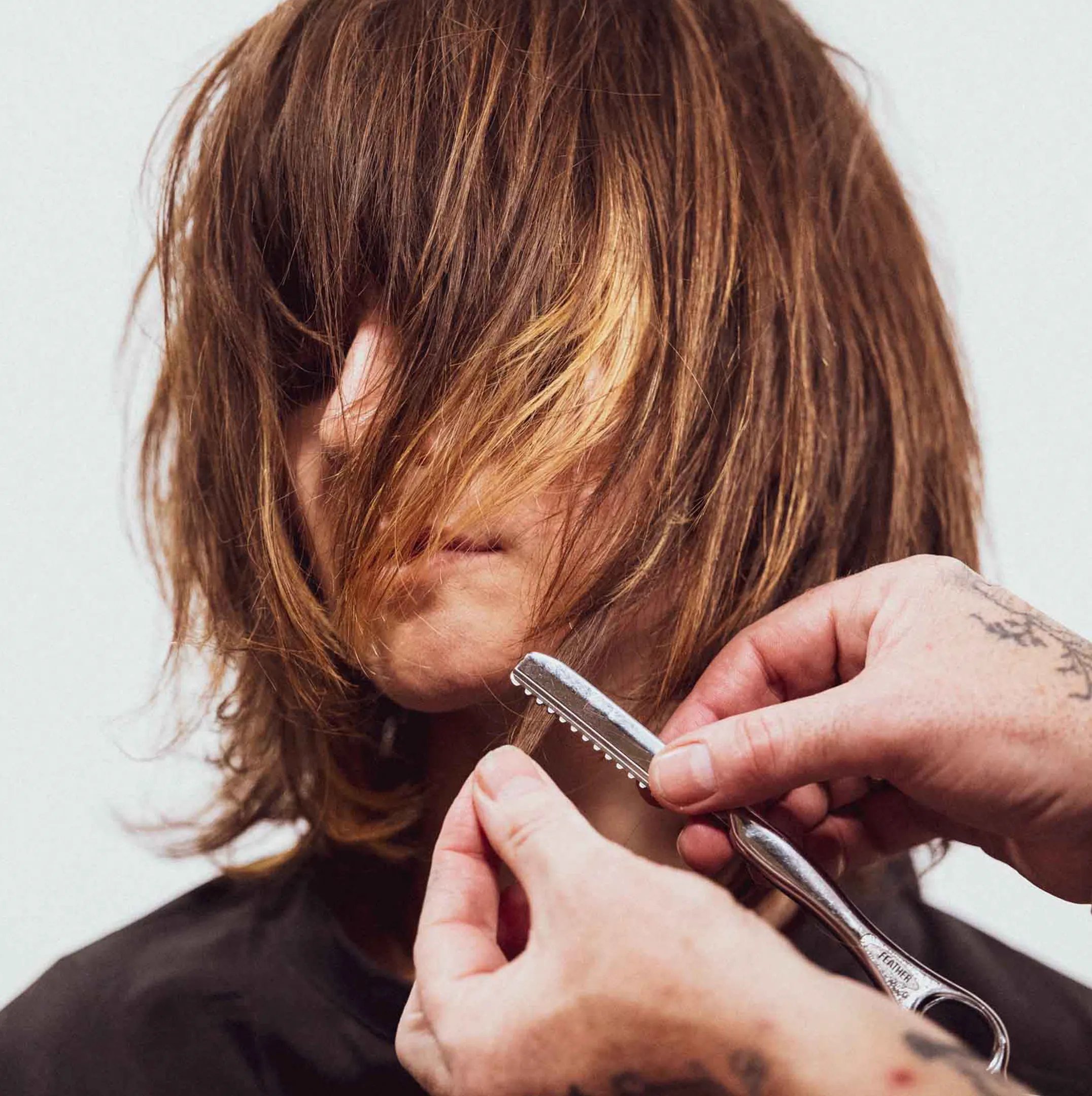 Modello che guarda di lato con capelli corti biondo platino che coprono metà del viso. 