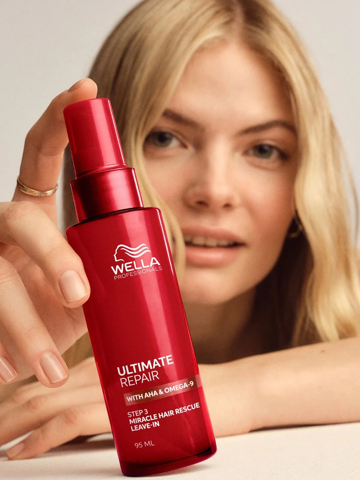 Blonde model holds a bottle of ULTIMATE REPAIR Miracle Hair Rescue.