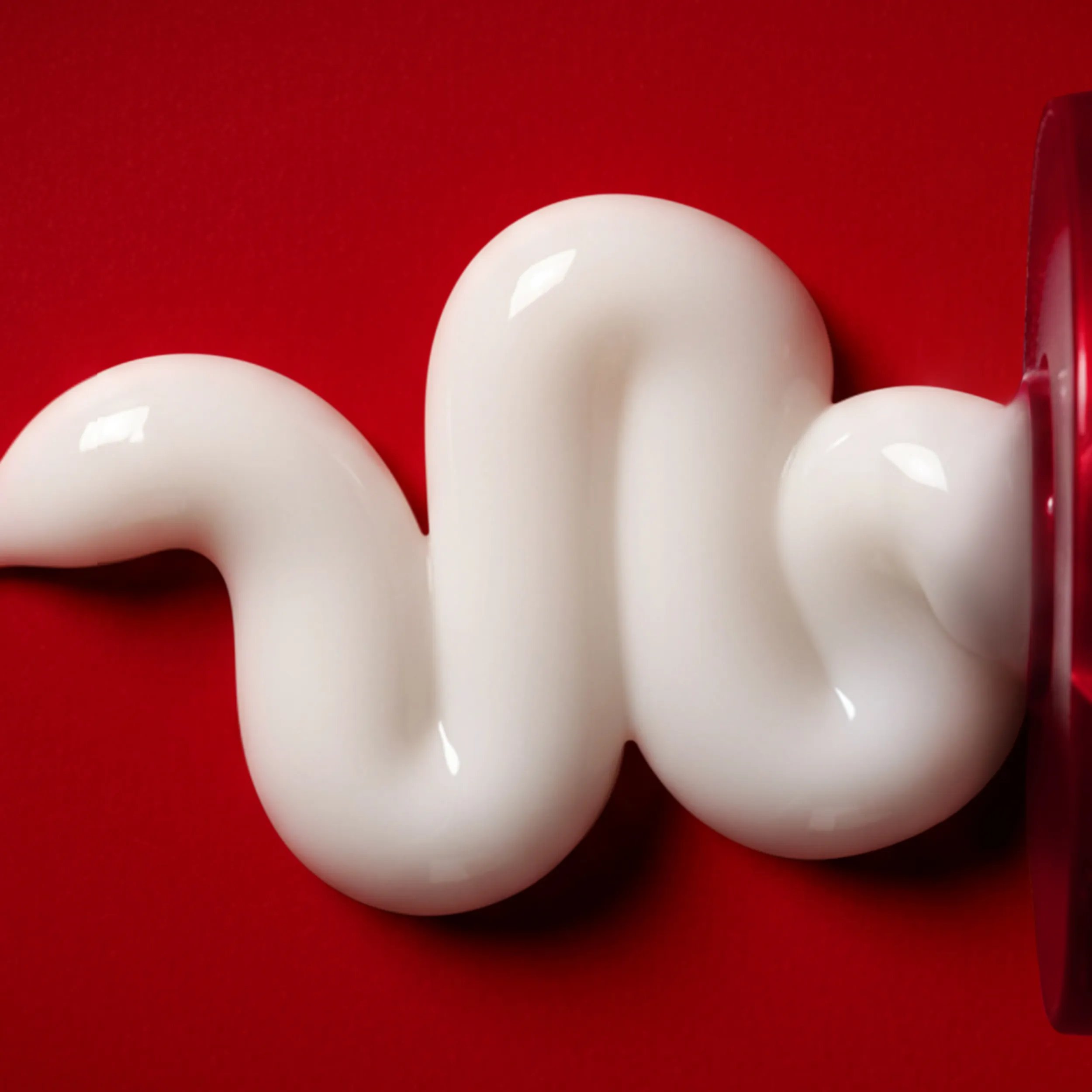 Cream squeezed onto a red background.