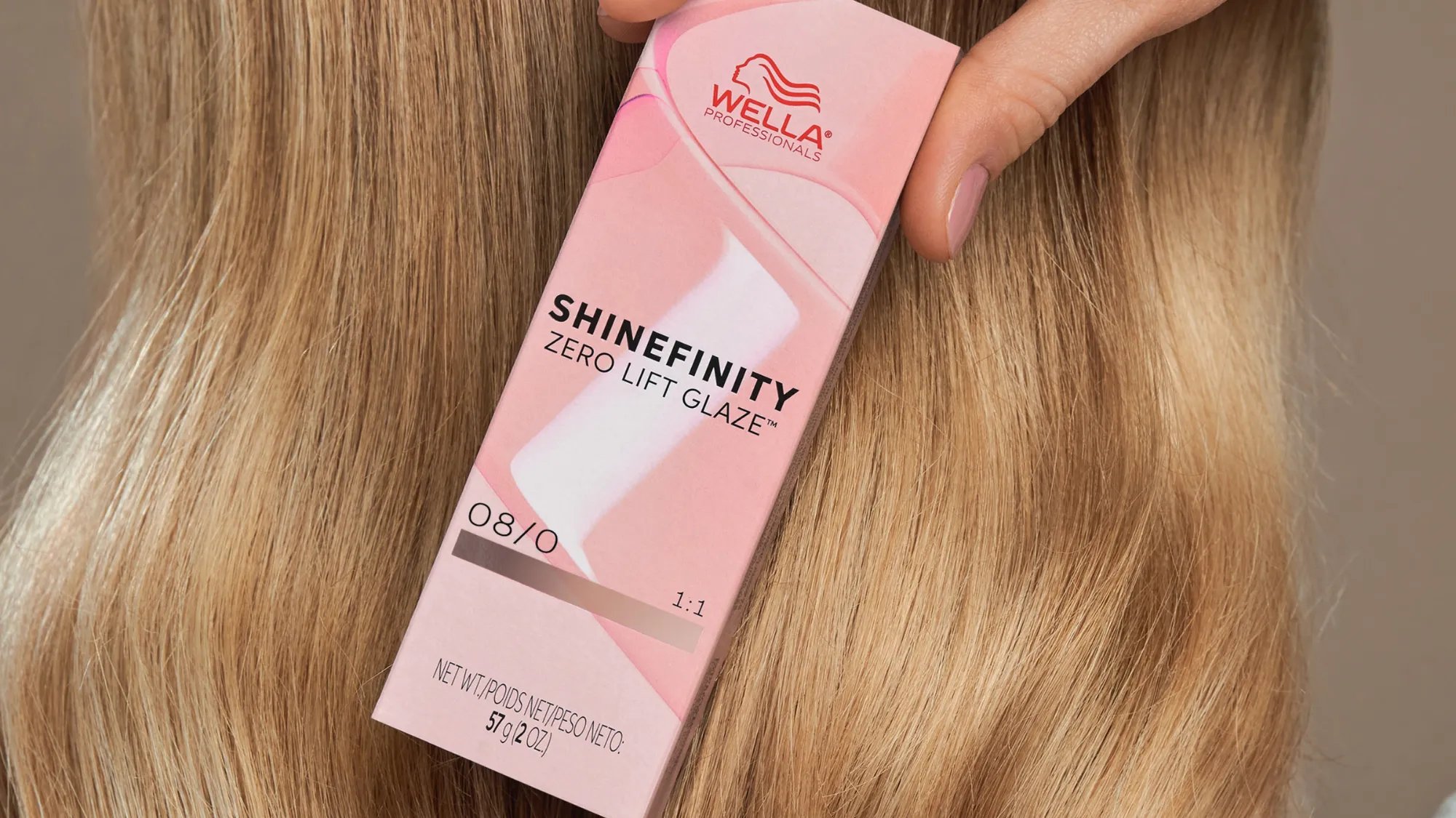 Blonde model holds a box of SHINEFINITY hair color.