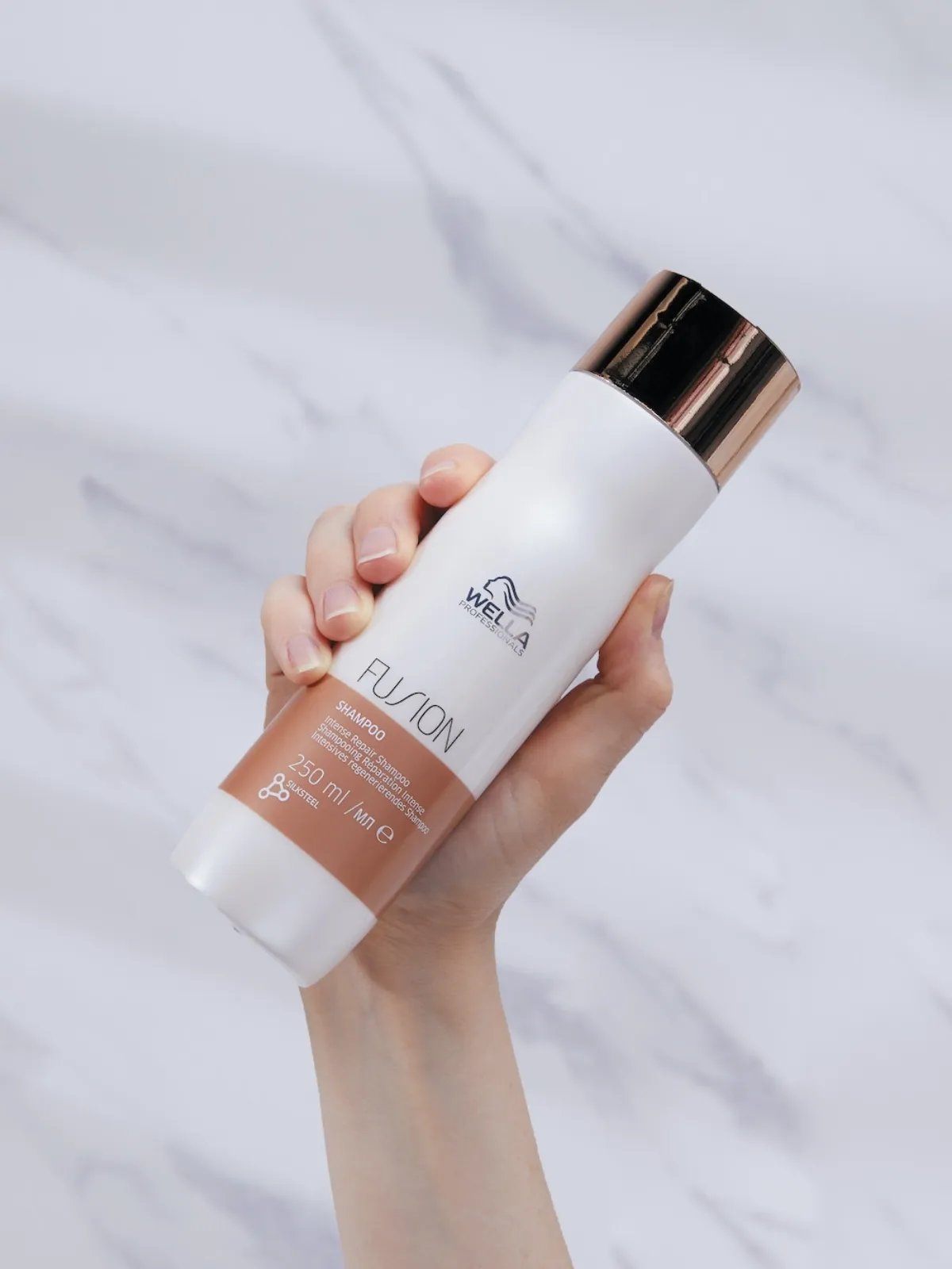 Model holds up a bottle of Fusion Intense Repair Shampoo.