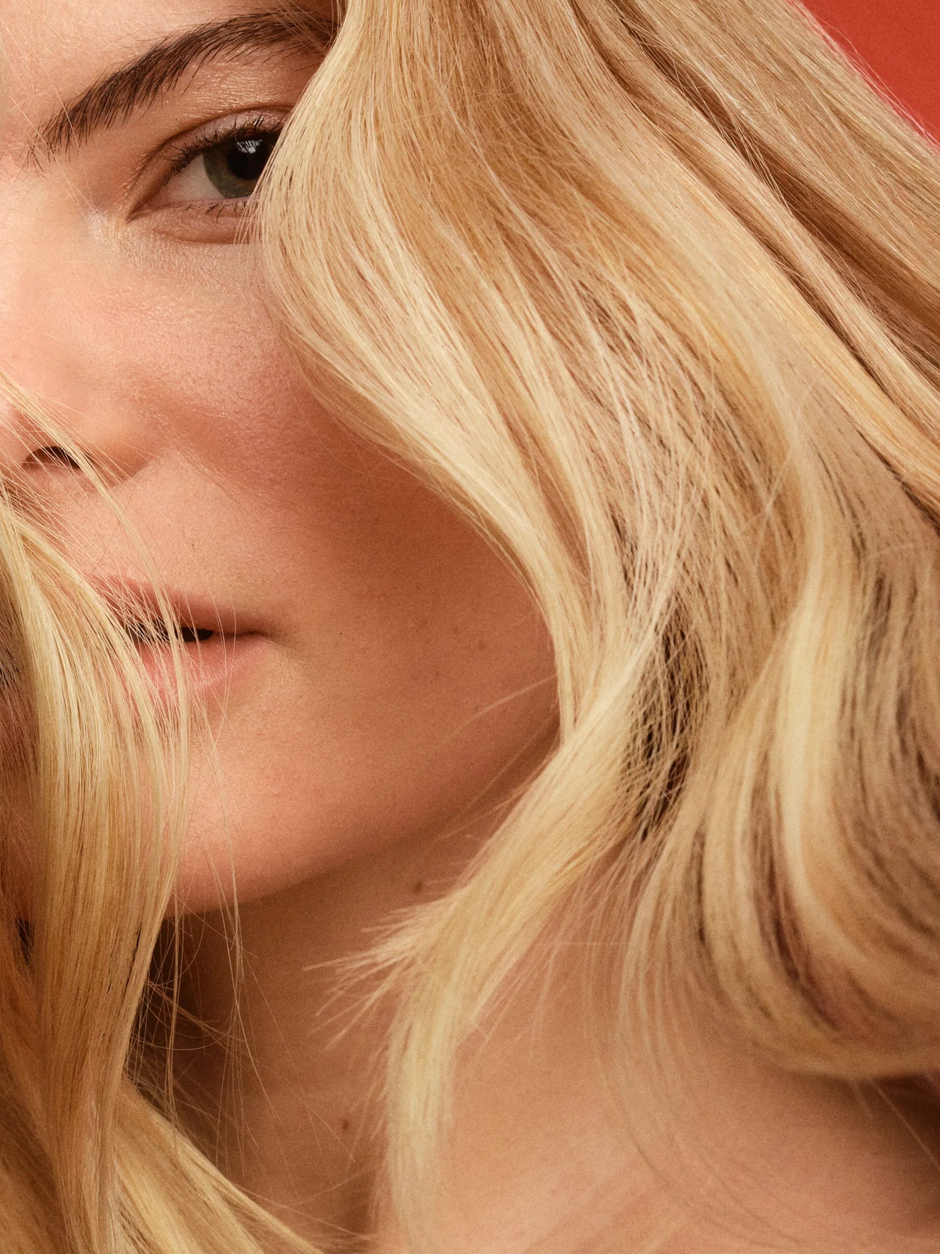Woman with wavy blonde hair covering part of her face.