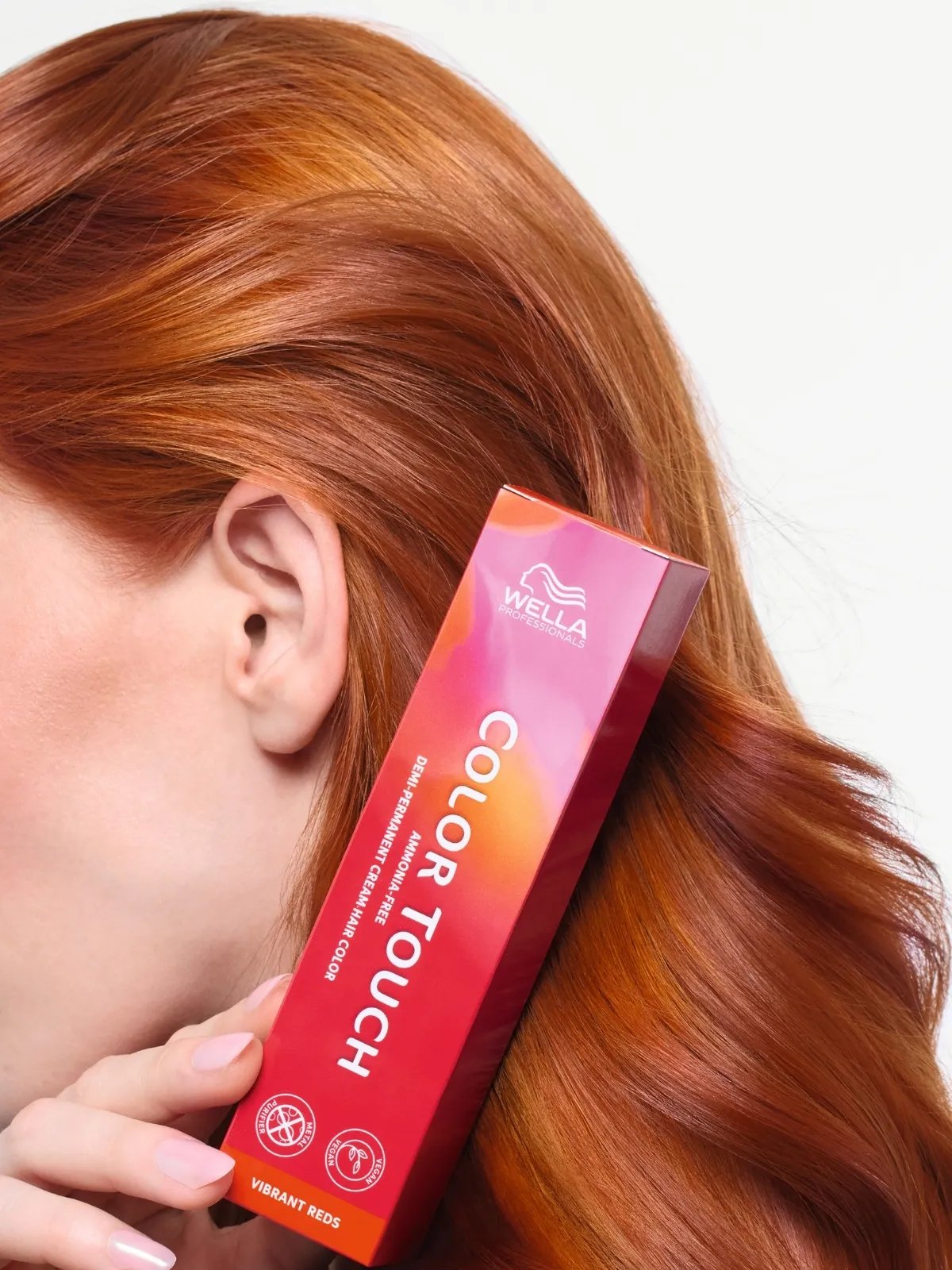 Red-haired model holding box of Color Touch hair color.