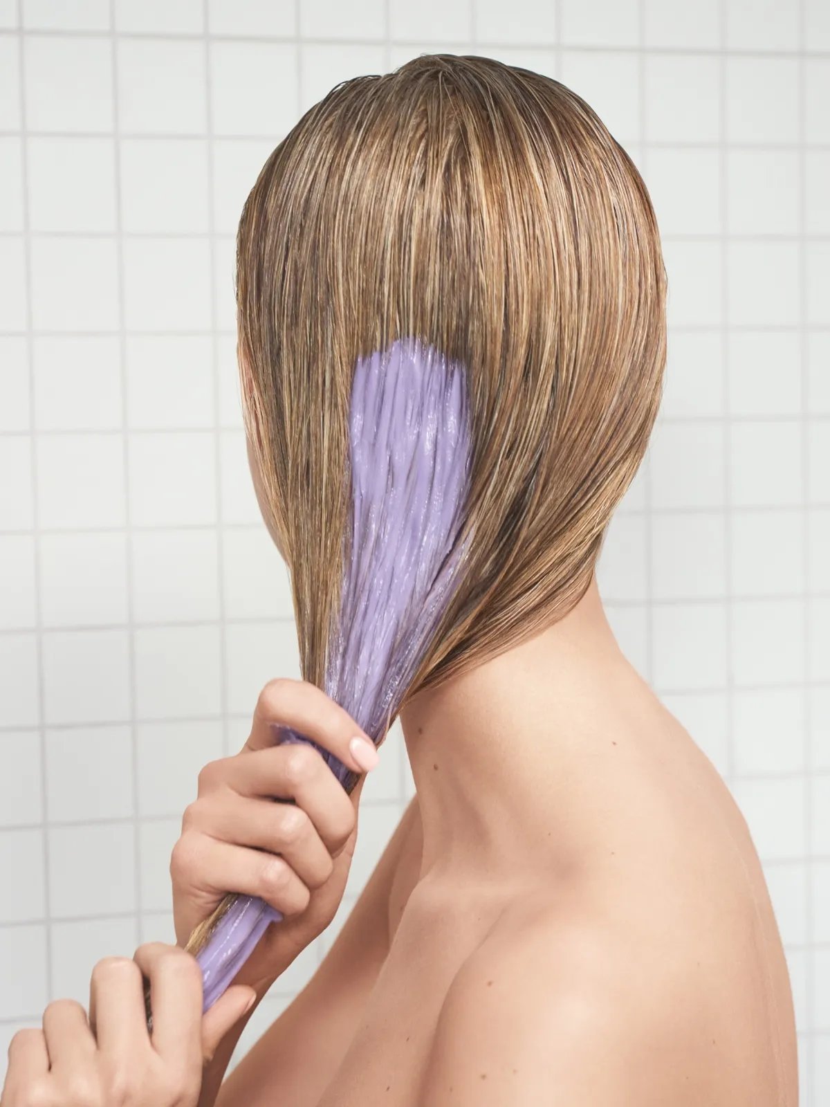 Model smooths purple conditioner through mid-lengths and ends of damp hair.