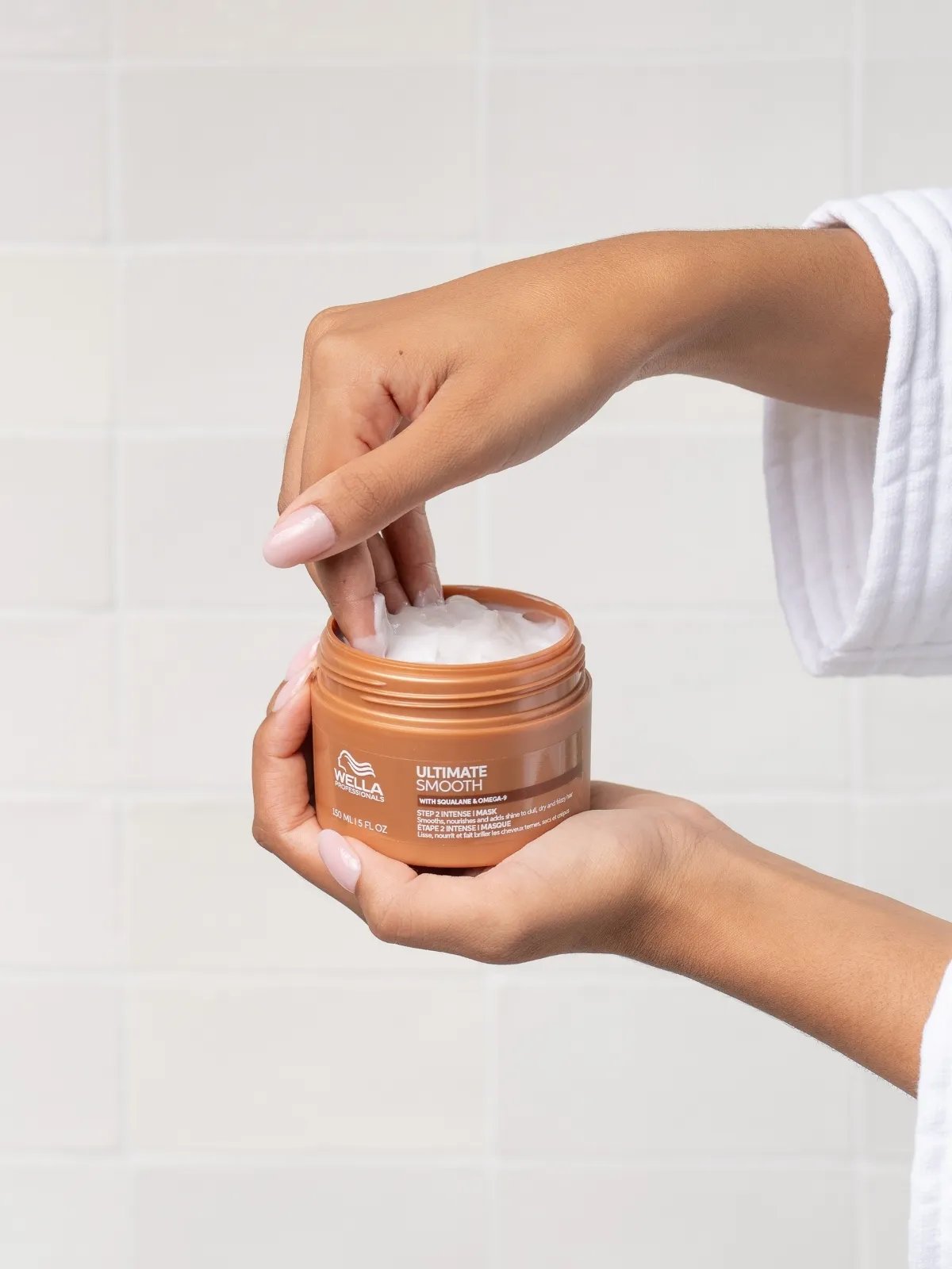Model takes a scoopful of ULTIMATE SMOOTH Intense Mask from tub.