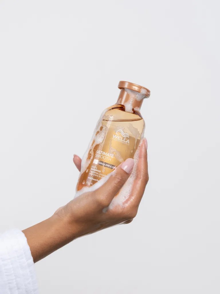 Model holding bottle of ULTIMATE SMOOTH Shampoo.