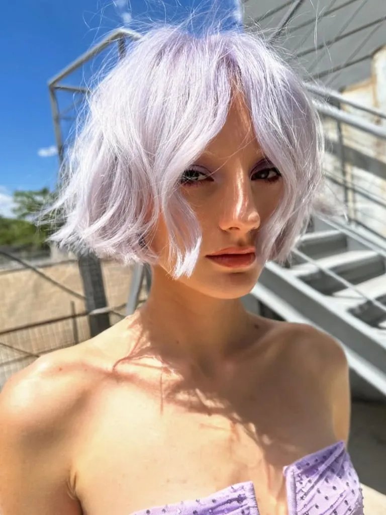 Model with pastel purple, chin-length bob haircut.