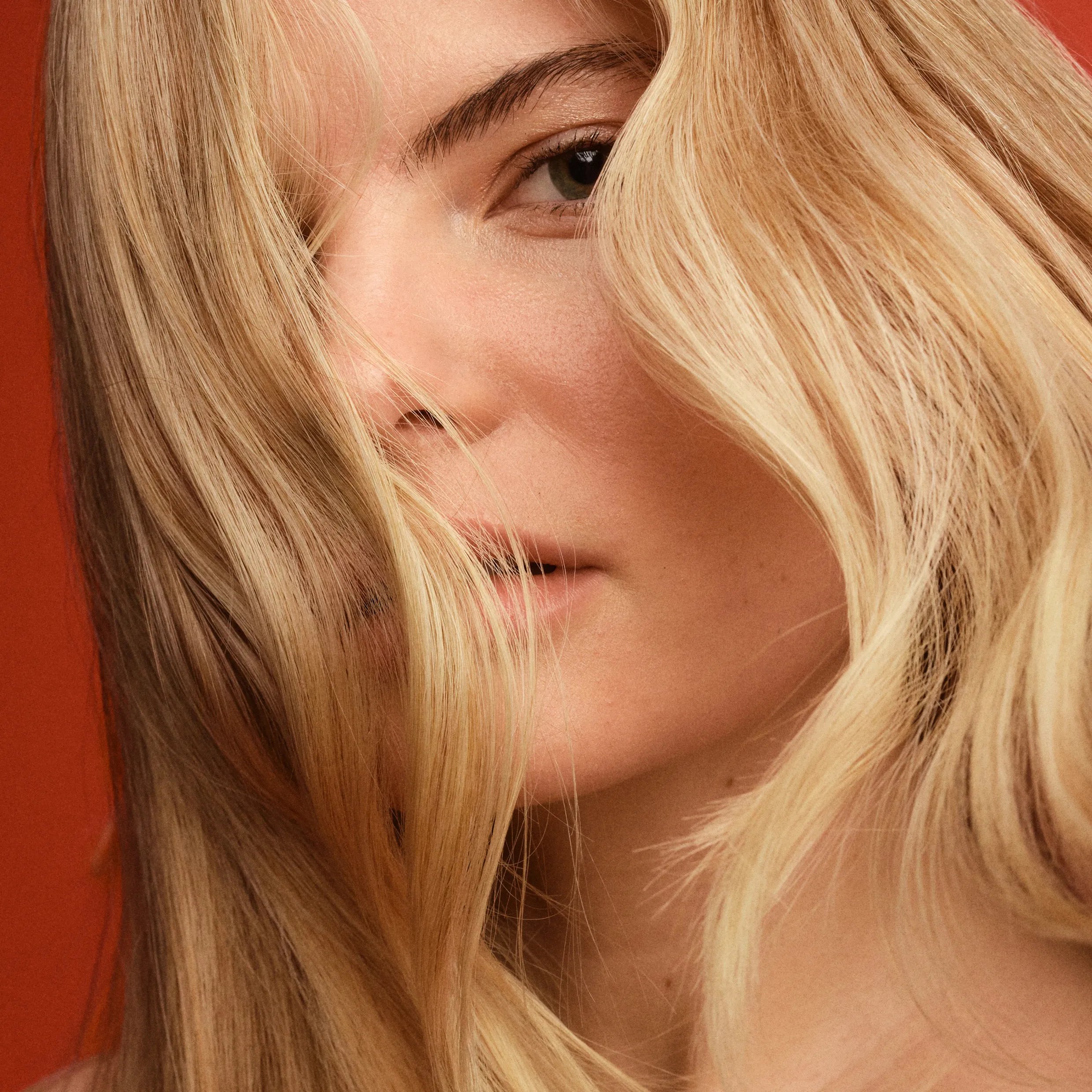 Woman with wavy blonde hair covering part of her face.