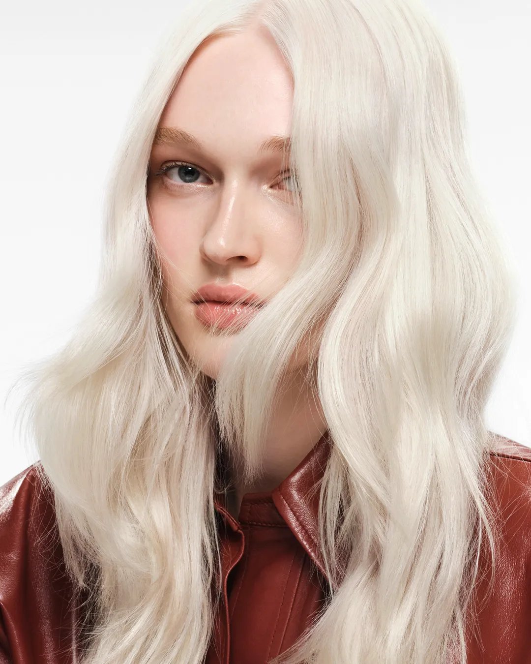 Close-up of the lengths and ends of a model’s icy blonde, wavy hair. 