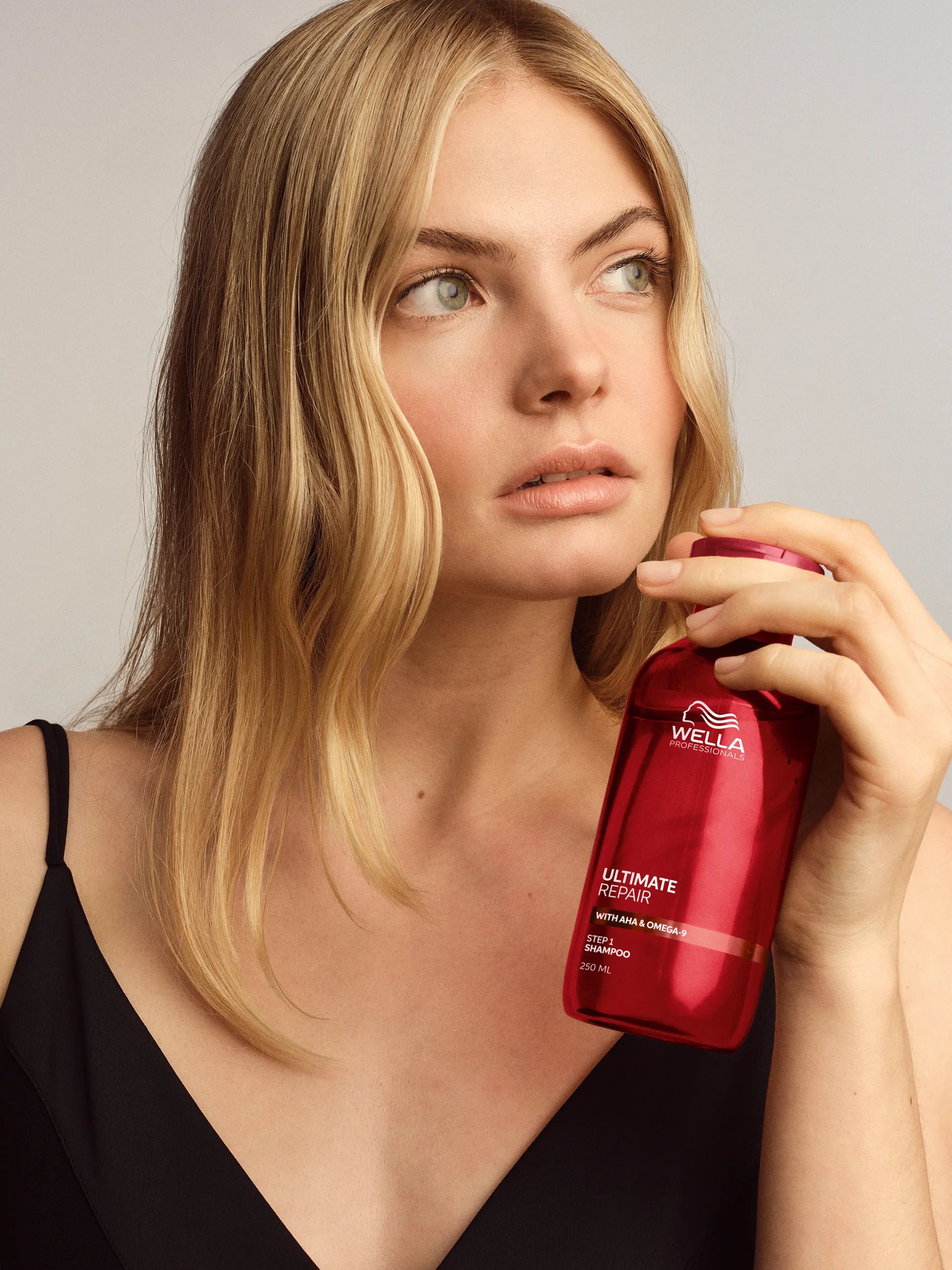 Model with long blonde hair holds Ultimate Repair Shampoo