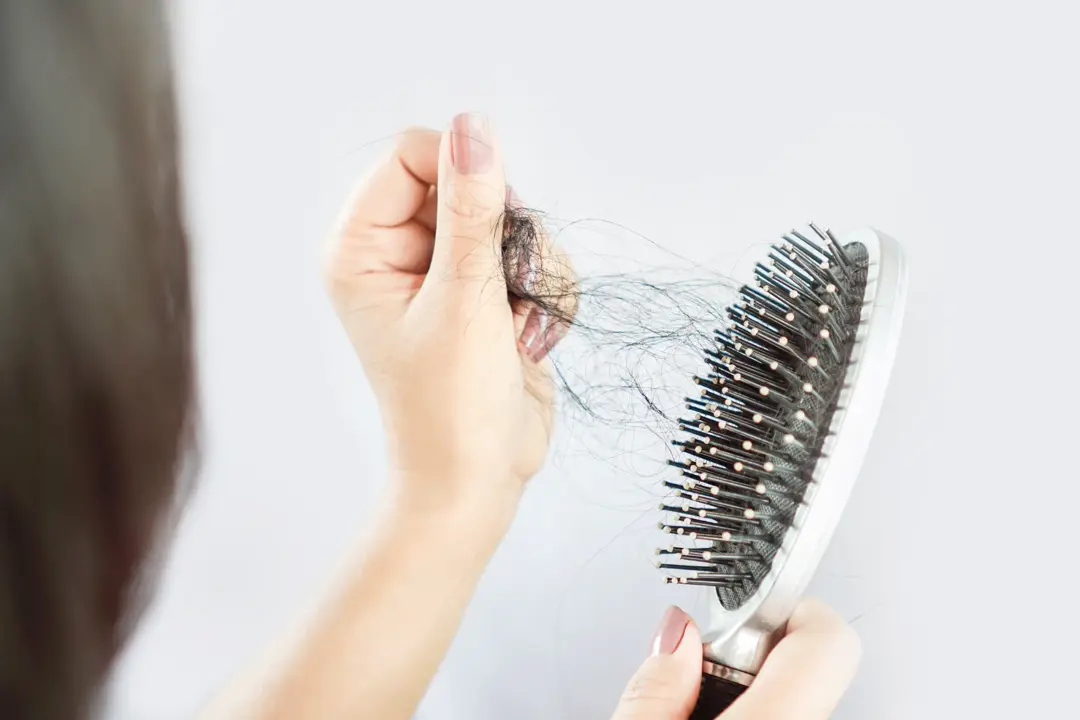 Hand pulling ball of hair out of a hairbrush