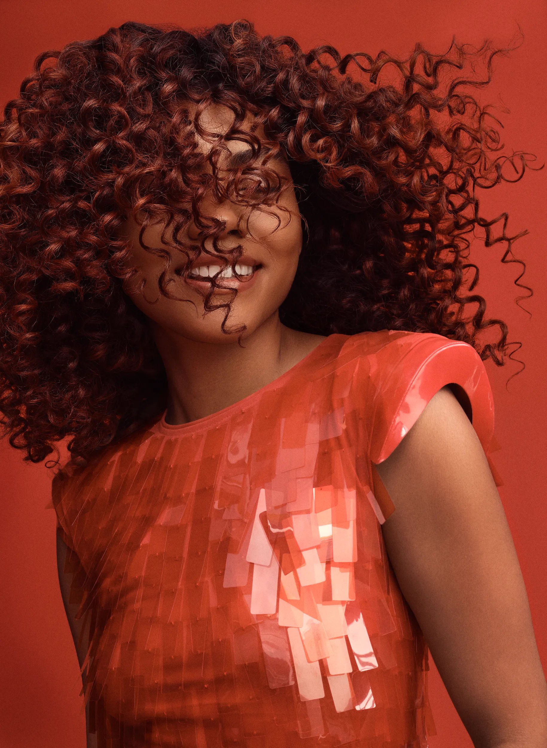 Close-up of a model with dark, curly hair covering their face.