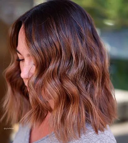 Side profile of woman with brown balayage bob styled in loose waves, created using Wella Professionals.