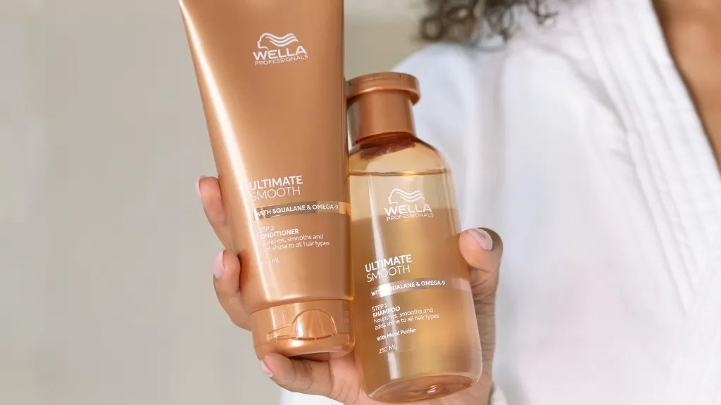 Model holds up bottles of ULTIMATE SMOOTH Conditioner and ULTIMATE SMOOTH Shampoo.