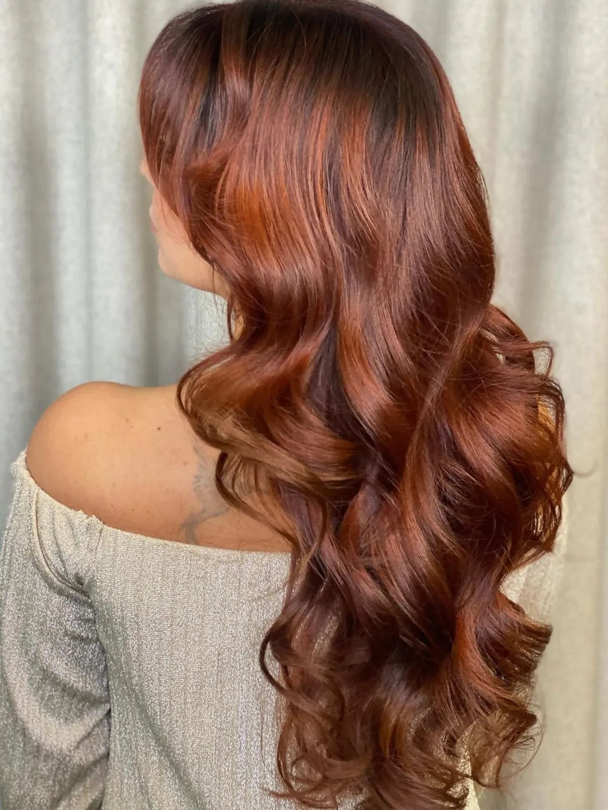 Model with long, loosely curled, copper auburn hair.