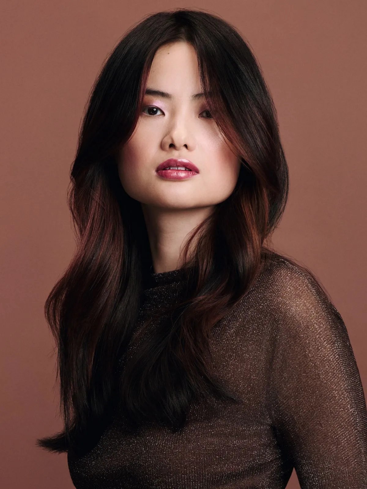 Model with espresso brown hair, wearing a brown top, against a brown background. 