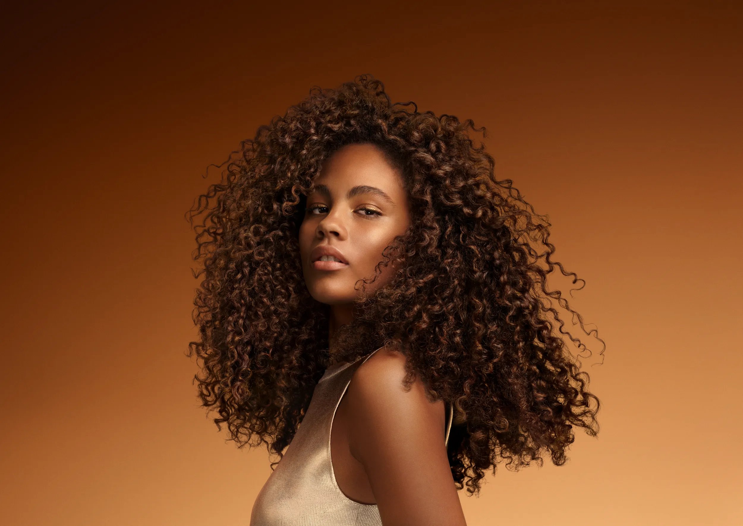 A woman with curly hair poses for a photo, gazing directly at the camera.
