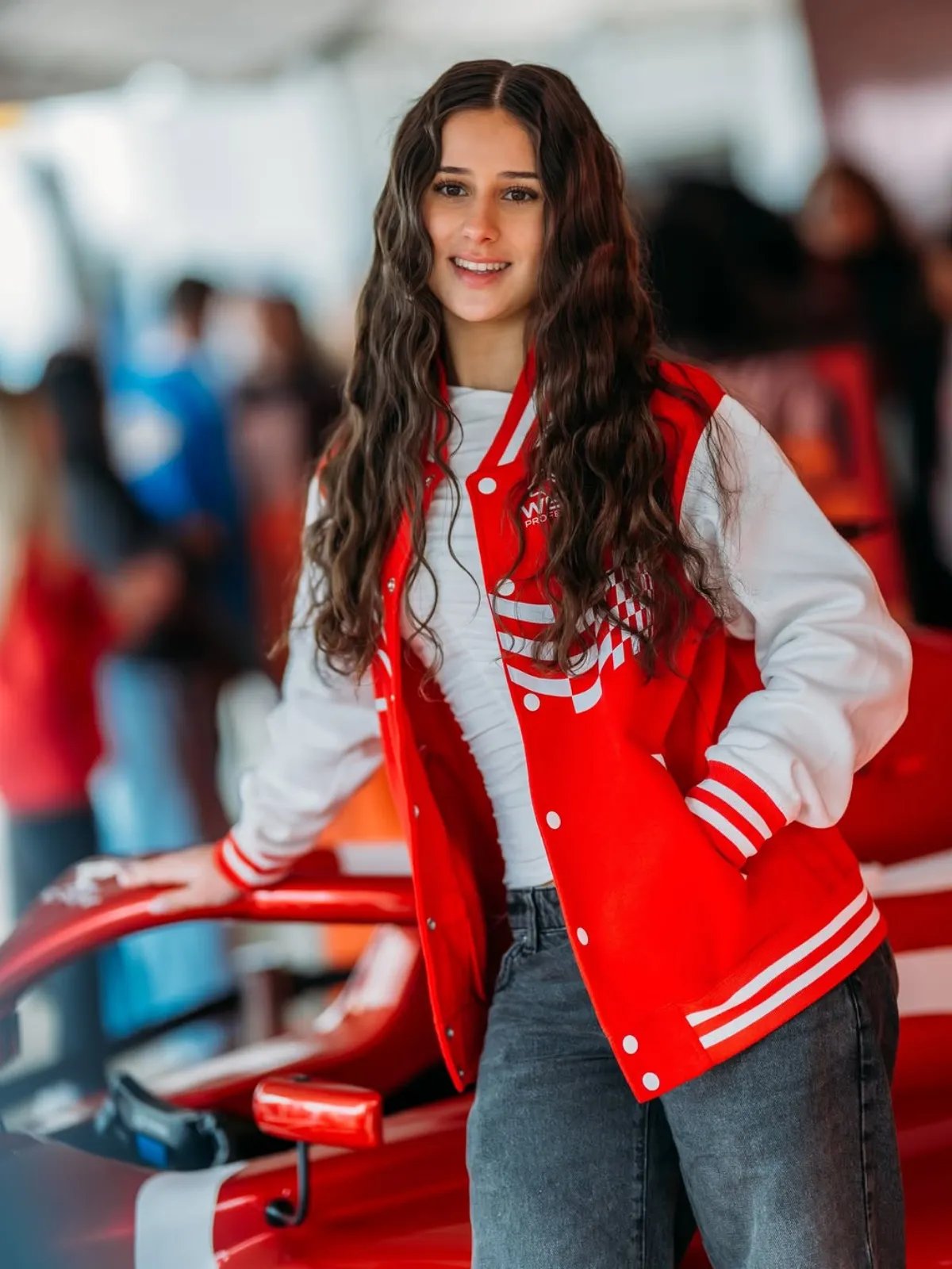 Joanne Ciconte poses next to her car, wearing a Wella red jacket