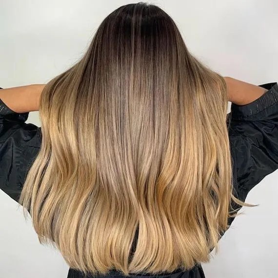 Model with long, wavy hair and light brown balayage, created using Wella Professionals. 