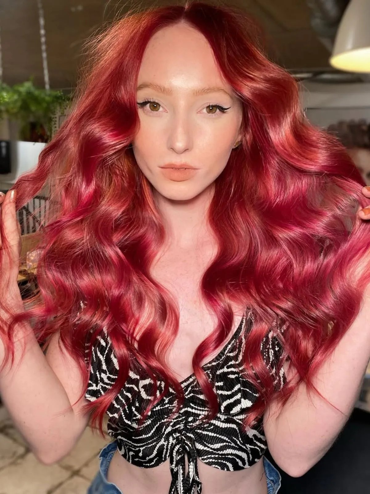 Model with long, ruby red hair styled in beachy waves. 
