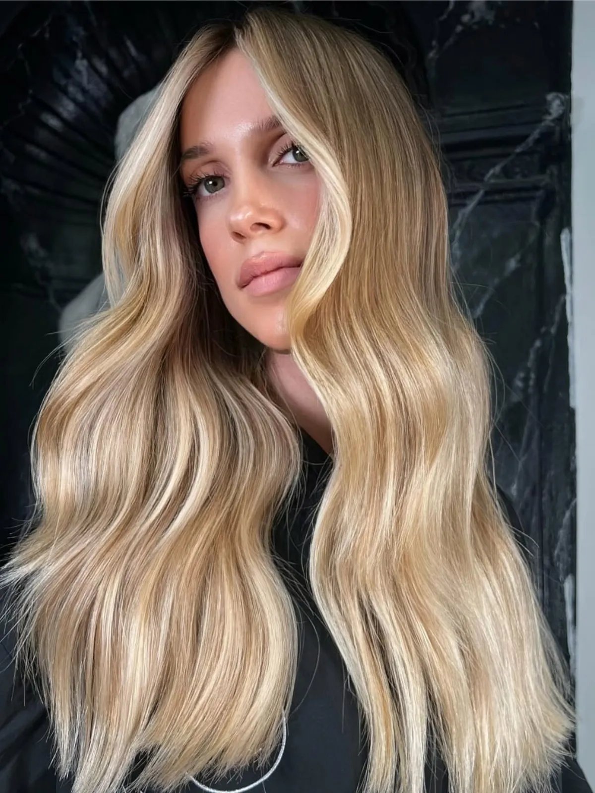 Model with long, honey blonde, wavy hair featuring a lighter face frame.