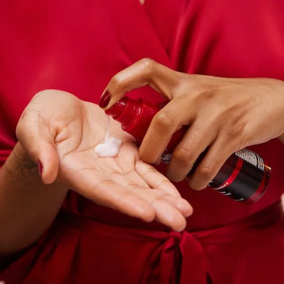 Model pumps ULTIMATE REPAIR Night Serum into palm of hand. 