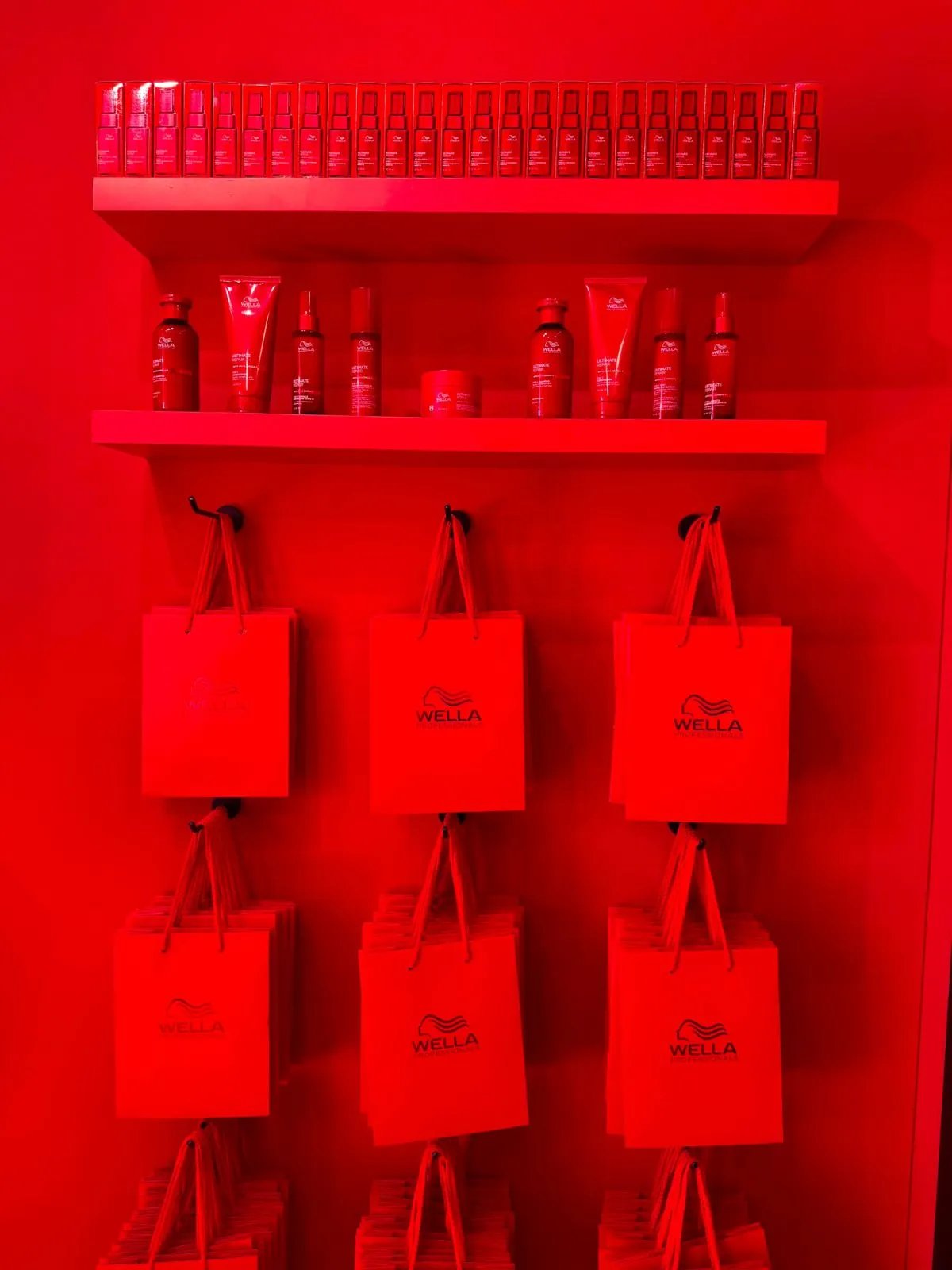 A red wall of Wella Professionals bags and ULTIMATE REPAIR products. 
