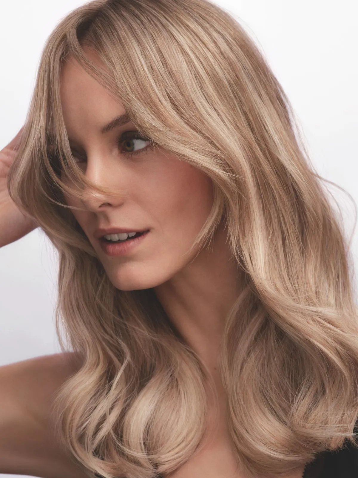 Model with cashmere blonde hair styled in a bouncy blow-dry.