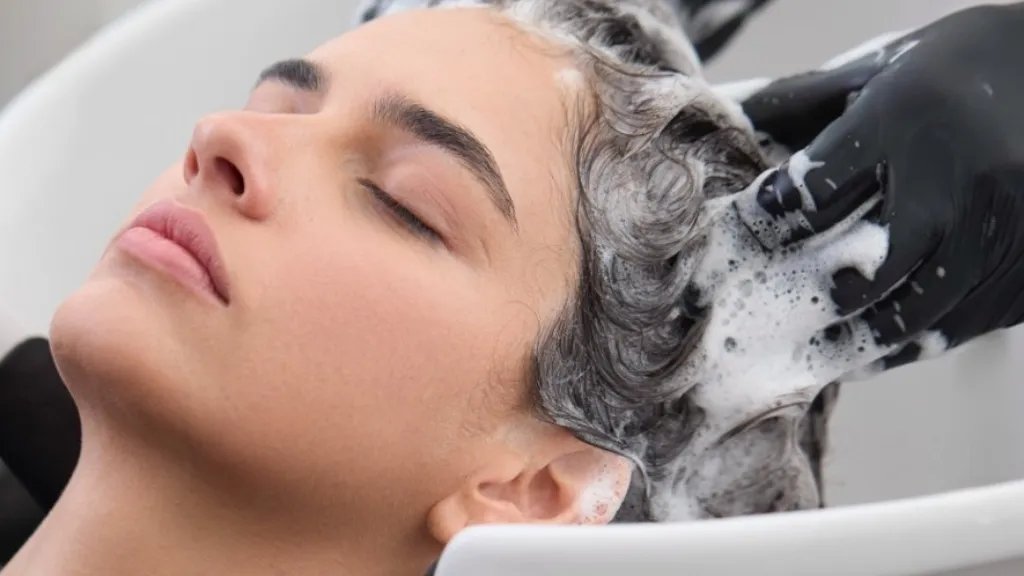 Model’s hair is washed by a hairstylist.