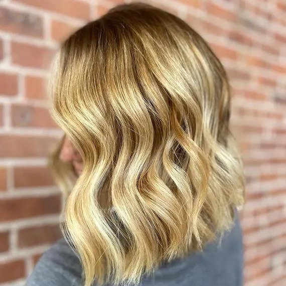 Model with shoulder-length, wavy hair in a bright golden blonde shade.
