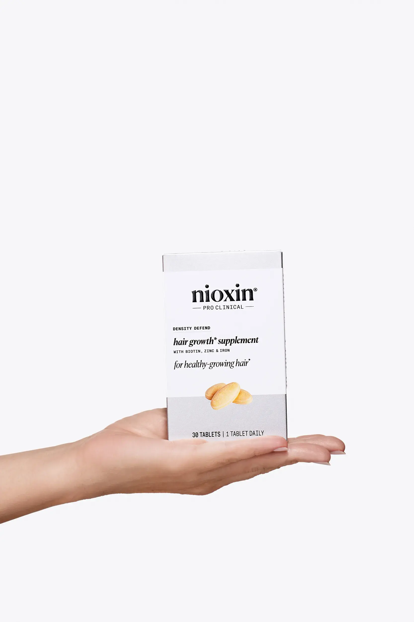 nioxin hair growth supplements in palm of hand against white background