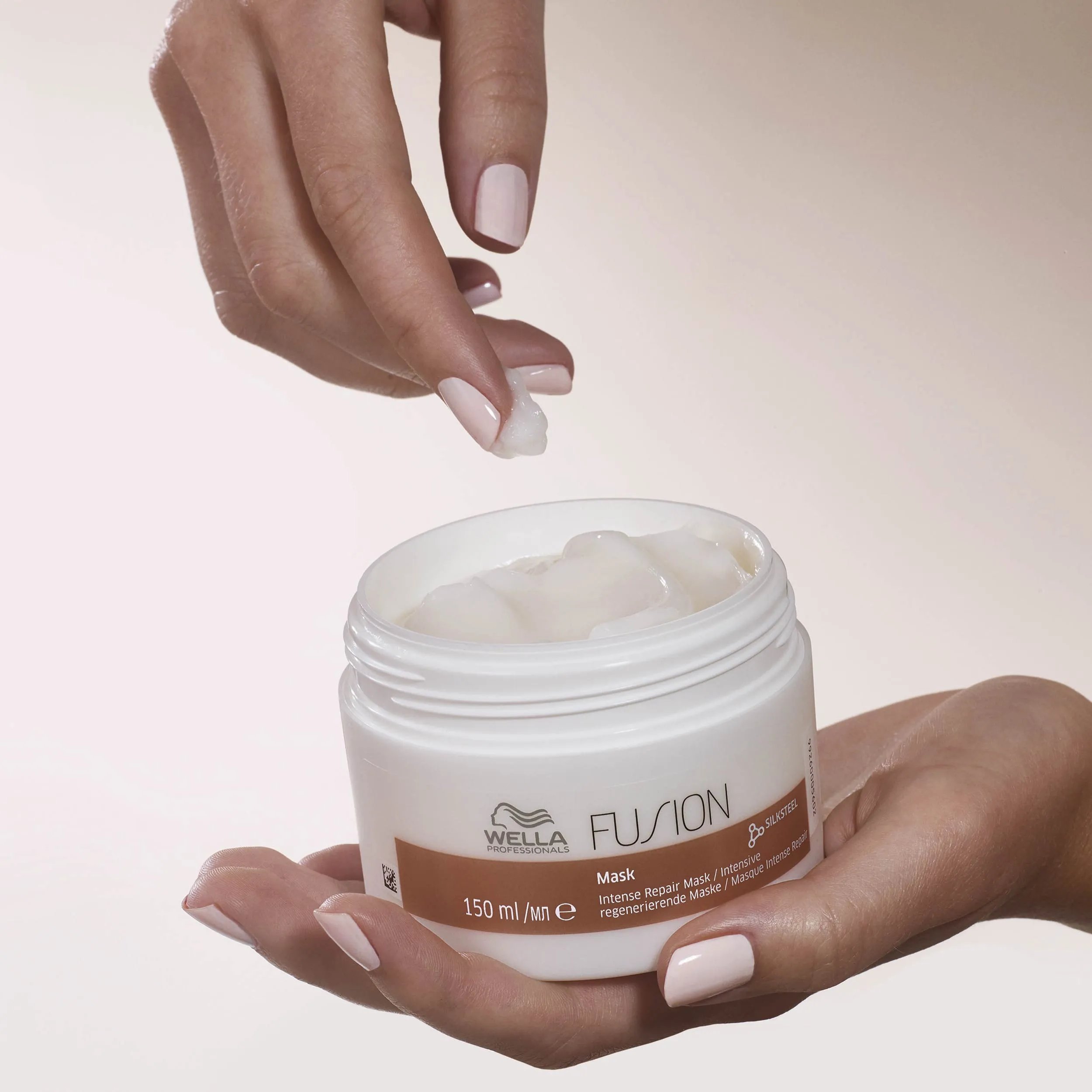 Model's hand scooping Fusion Intense Repair Mask from the jar