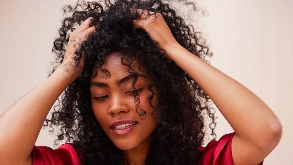 Model runs hands through the roots of their curly hair.