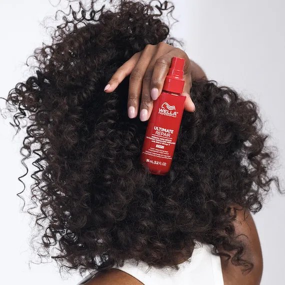 Back of model’s head. They have dark, curly hair and they’re holding up
ULTIMATE REPAIR Miracle Hair Rescue.