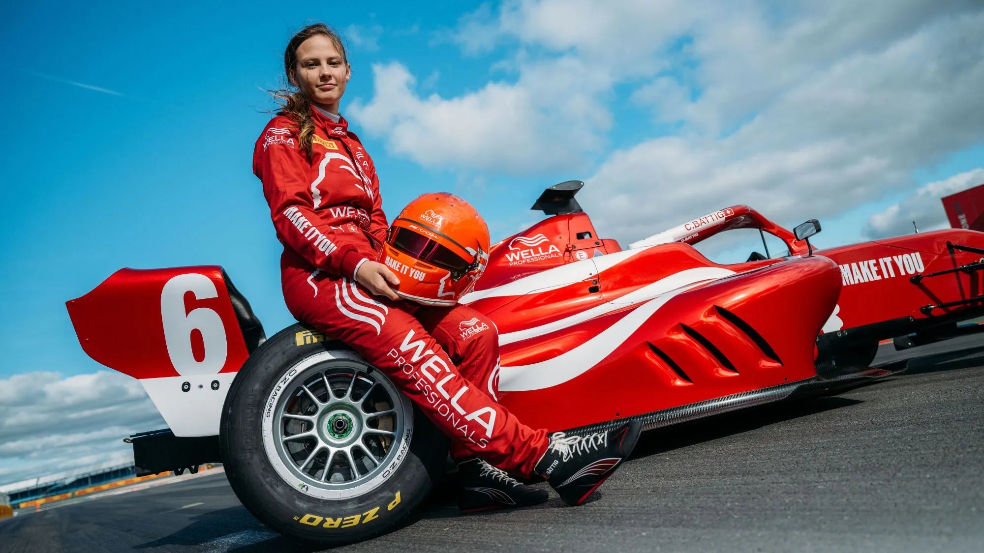 Chiara Bättig wearing her Wella red suit and posing beside the MAKE IT YOU racecar.