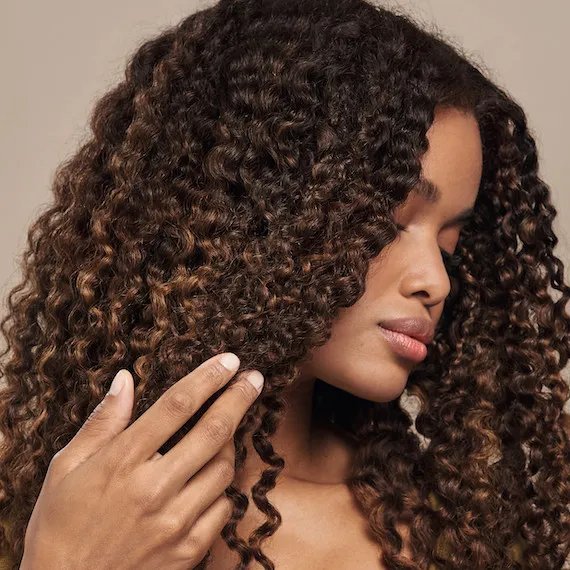 Model with long, glossy, curly, dark brown hair.