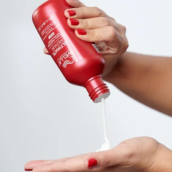 Model pours ULTIMATE REPAIR Shampoo into palm of hand.