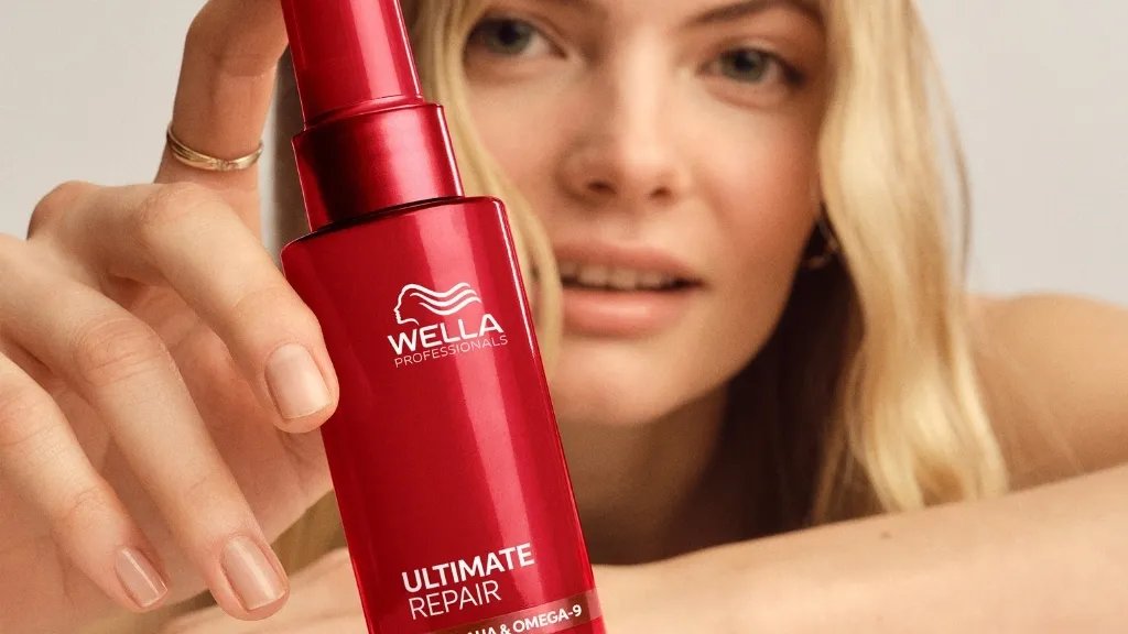 Blonde model holds bottle of ULTIMATE REPAIR Miracle Hair Rescue.