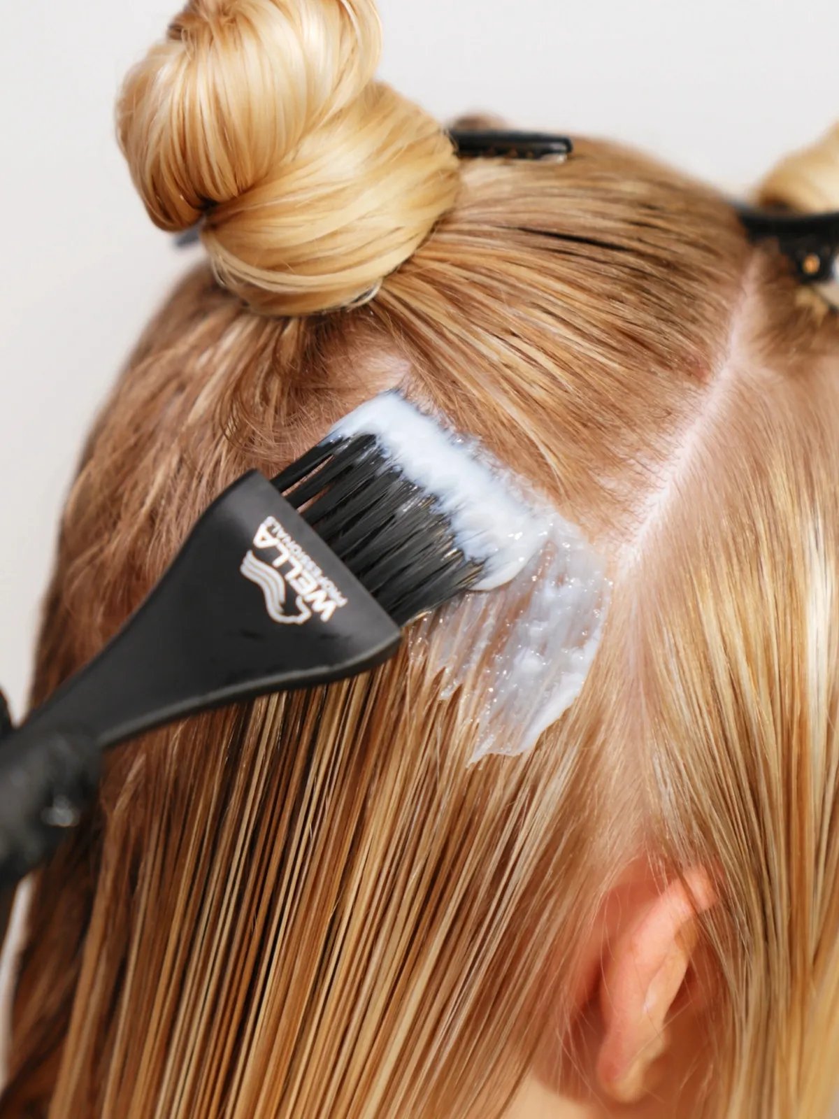Close-up of Wella Professionals stylist applying highlights to blonde hair.